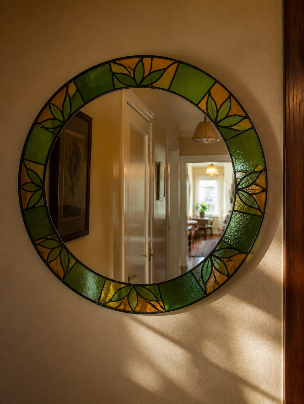 Mirror edged with a painted glass border in a bright hallway